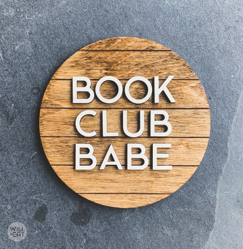Image of a wooden sign with white letters that read "book club babe."