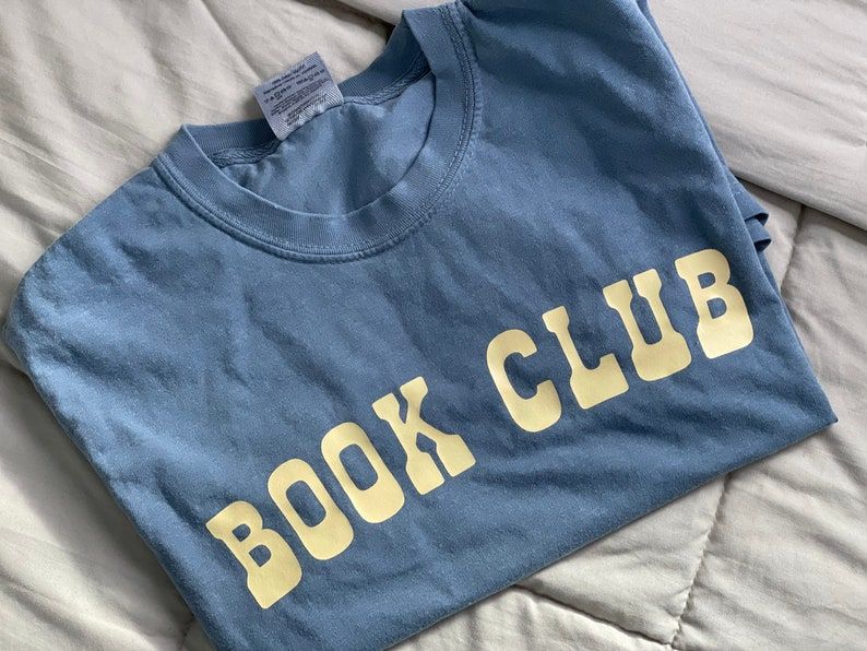 Blue t-shirt with light yellow font reading "book club."