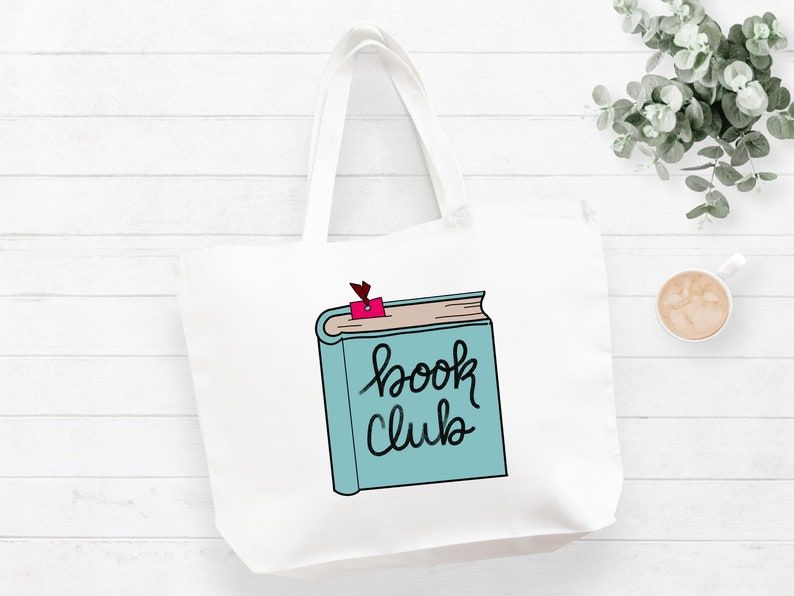 White tote bag on a white background. There is a blue book on the tote which reads "book club."