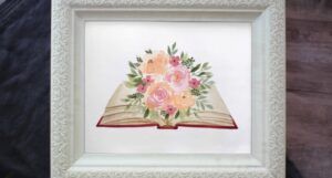 Watercolor picture of book with flowers blooming from it.