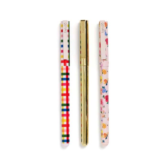set of three pens: one is solid gold, one in rainbow plaid, and one in a pink rose pattern
