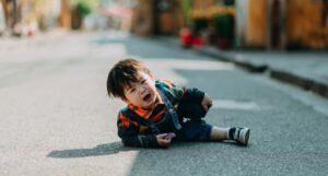crying Asian child lying on road