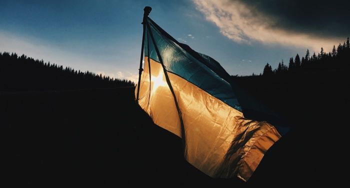 Ukranian flag waving in the wind against a dark landscape
