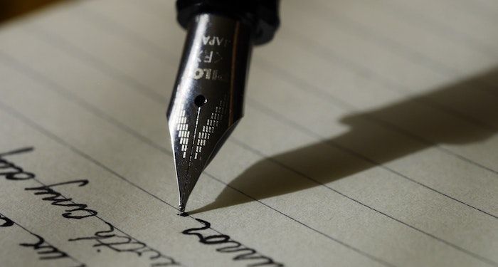 a photo of a fountain pen writing on a lined piece of paper