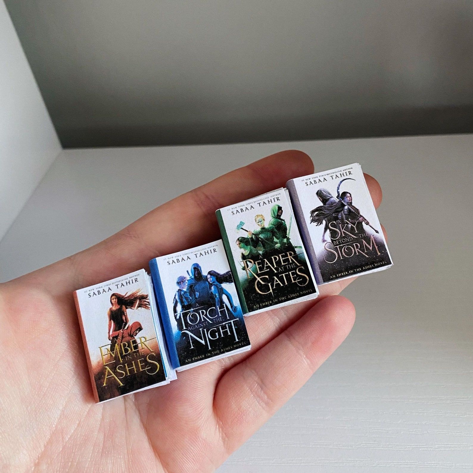 Four mini books with the covers of the Ember in the Ashes series