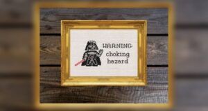 a cross-stitch pattern of a small Darth Vader next to the text "Warning: Choking Hazard"