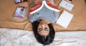 light-skinned asian woman lying down reading