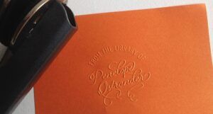 an orange sheet of paper embossed with the words "from the library of Penelope Ostrander"