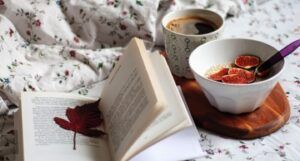 breakfast (with a cup of coffee and some oatmeal and figs) and a book on a floral sheet