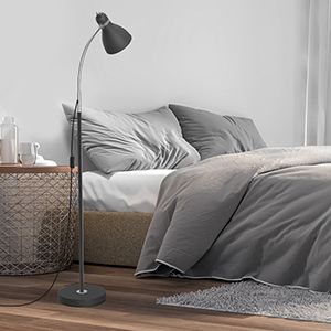 a photo of a gooseneck floor lamp with a metal shade by a bed