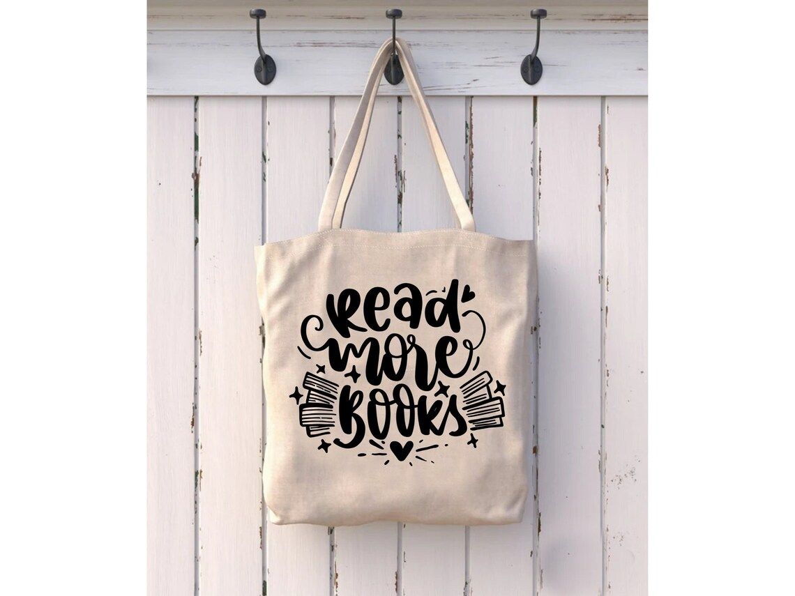 Canvas tote hanging on a coat hook. The tote reads in black font "read more books."