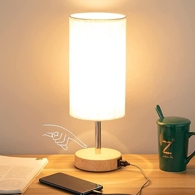 a photo of a reading lamp with a round shade. An illustration of a hand is touching the base.