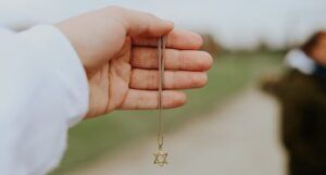 a photo of a hand holding a Star of David gold necklace