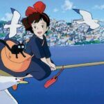 a still from Kiki's Delivery Service showing her on a broom with a cat smiling at seagulls flying by over the water