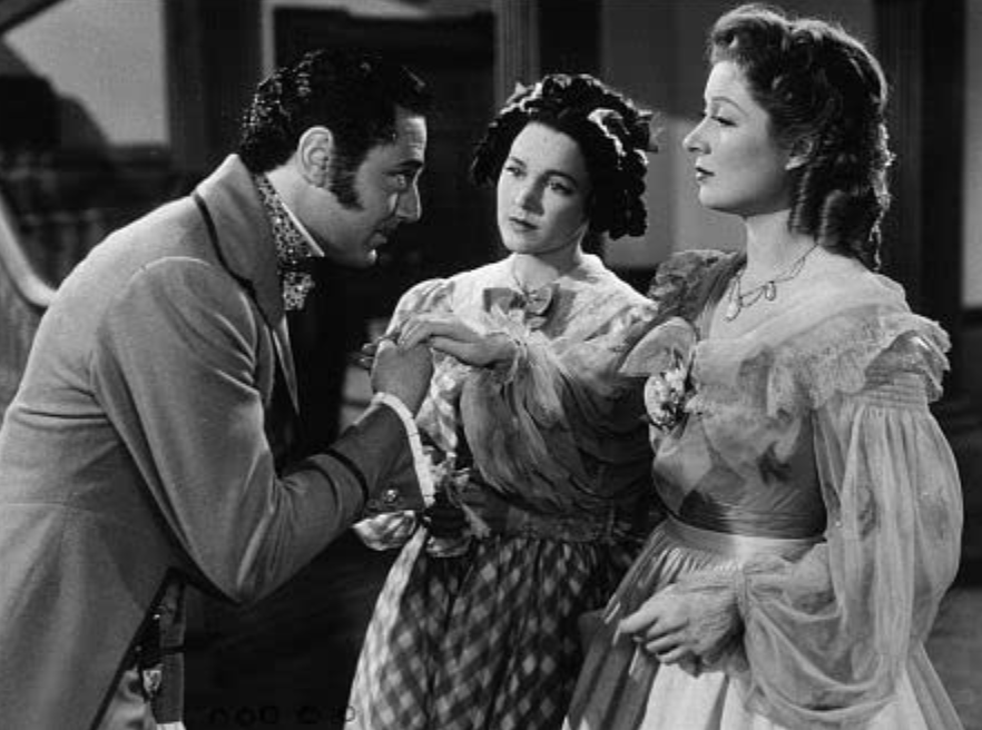 A black & white image of Laurence Olivier as Mr. Darcy, placing a kiss on the hand of Germaine Greer as Lizzie Bennet, while being watched by Maureen O'Sullivan playing Jane Bennet. 