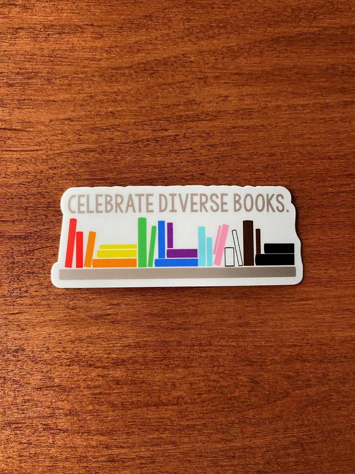 diverse rainbow book stack sticker against a woof surface