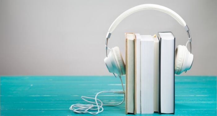 Image of white headphones on top of a stack of books.
