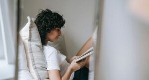 Image of a person with olive skin reading a book in a comfortable nook