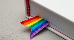 a photo of a white book with a rainbow ribbon bookmark