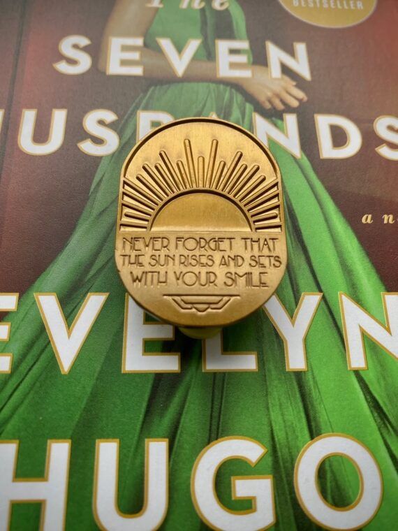 Evelyn Hugo quote on a golden pin with a sun