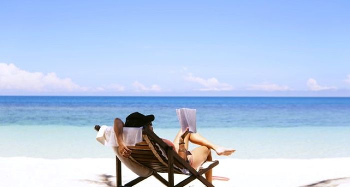 a person reading on the beach in a beach chair