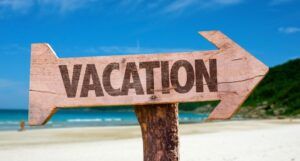 Image of a wooden sign in the shape of an arrow reading "vacation."