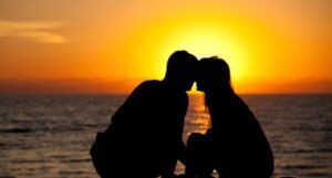 the silhouette of two people leaving in close to one another on a beach at sunset