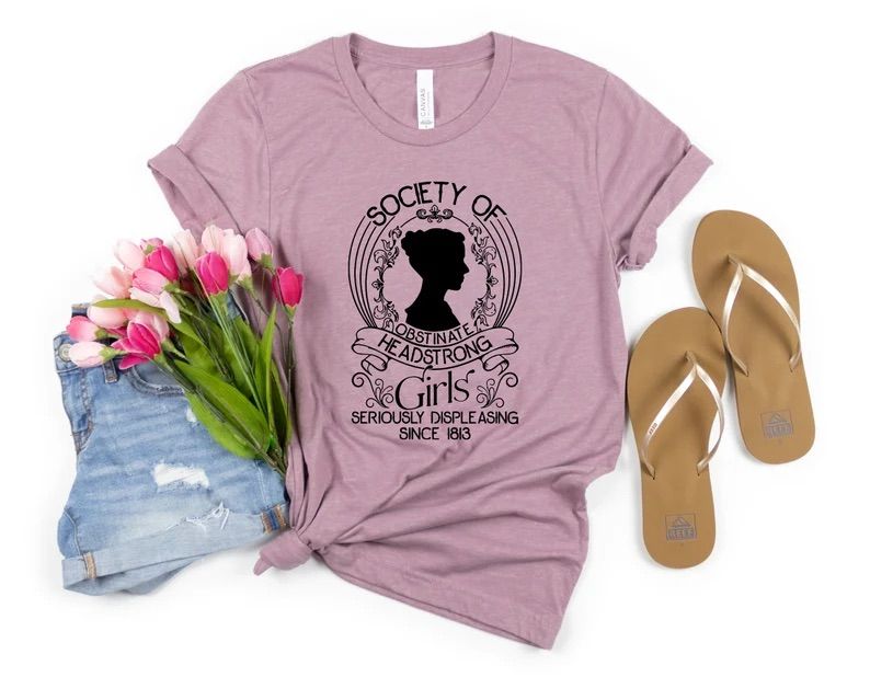 Photo of a pink t-shirt with an outline of Jane Austen's head with the text Society of obstinate headstrong girls seriously displeasing since 1813.