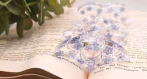 A clear acrylic book page holder with painted blue flowers
