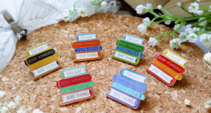 enamel pins shaped like a stack of books with the text "You say book hoarder like it's a bad thing"