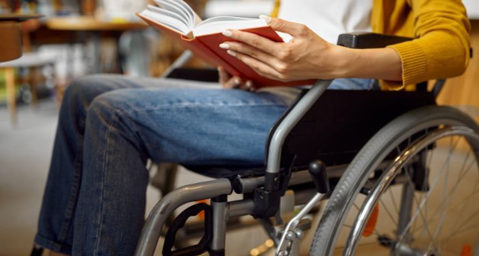 image of wheelchair user reading a red book.