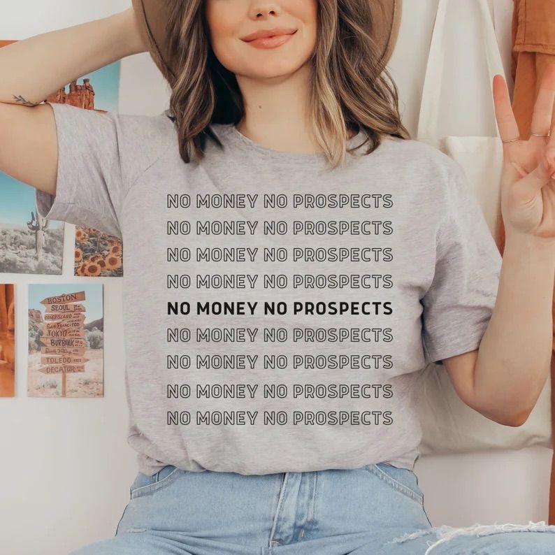 Photo of a woman wearing a grey t-shirt with the text no money no prospects all over it, only outlined in each line exceot the middle one, which is black. 