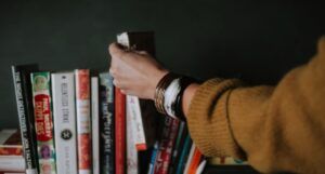 person reaching for book from shelf