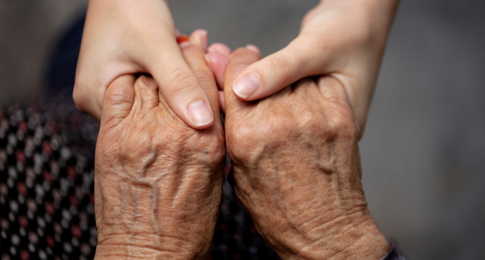 a photo of a young person holding an elderly person's hands