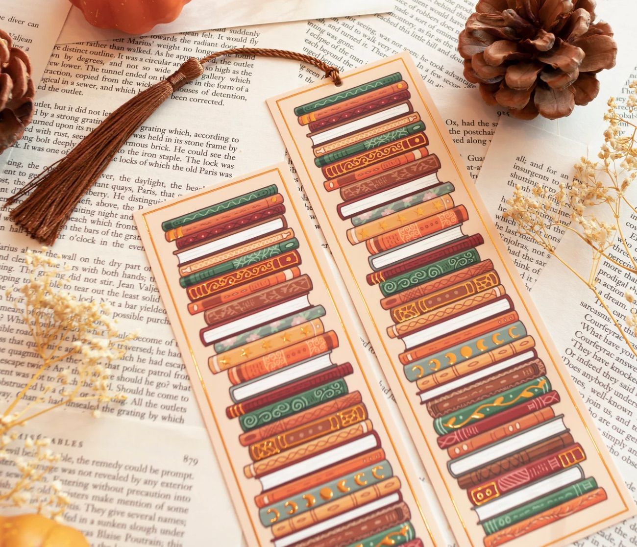 Image of two bookmarks that feature fall colored book stacks. 