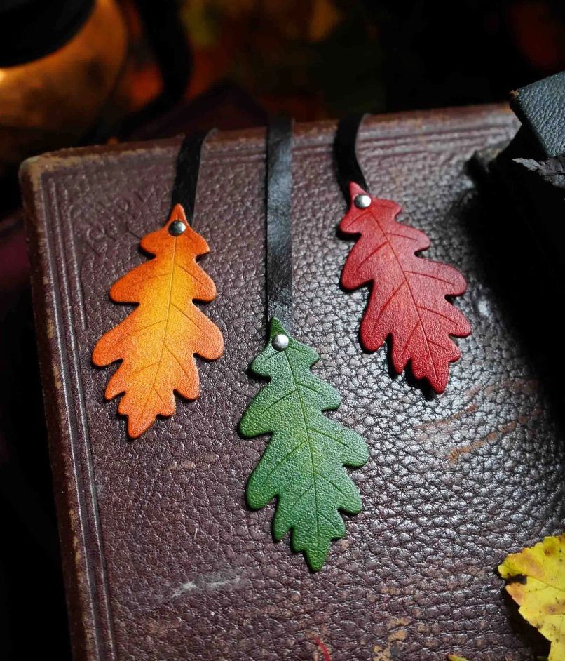 Image of three leather bookmarks in the shape and color of autumn leaves. 
