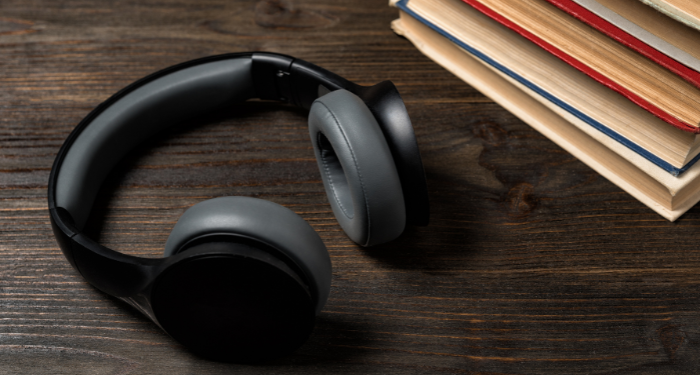 a photo of black headphones beside a stack of books