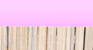 a photo of a bookshelf of manga from behind with a pink background
