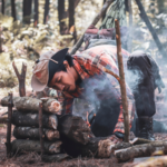 a photo of a man starting a campfire in the woods