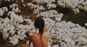 tan woman's back around flowery tree
