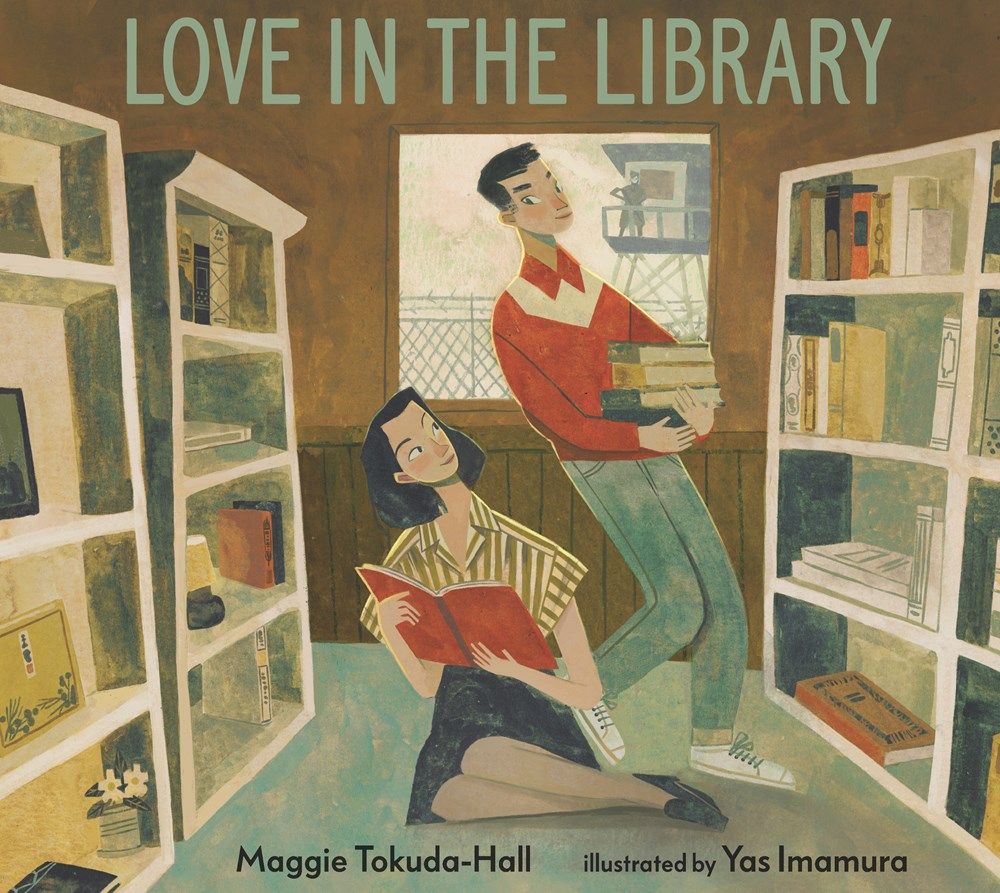 Love in the Library Book Cover, showing a Japanese woman looking up at white man in a library, both holding books in their arms. The woman is seated with her leg folded to one side on the floor while the man in standing and looking down at her