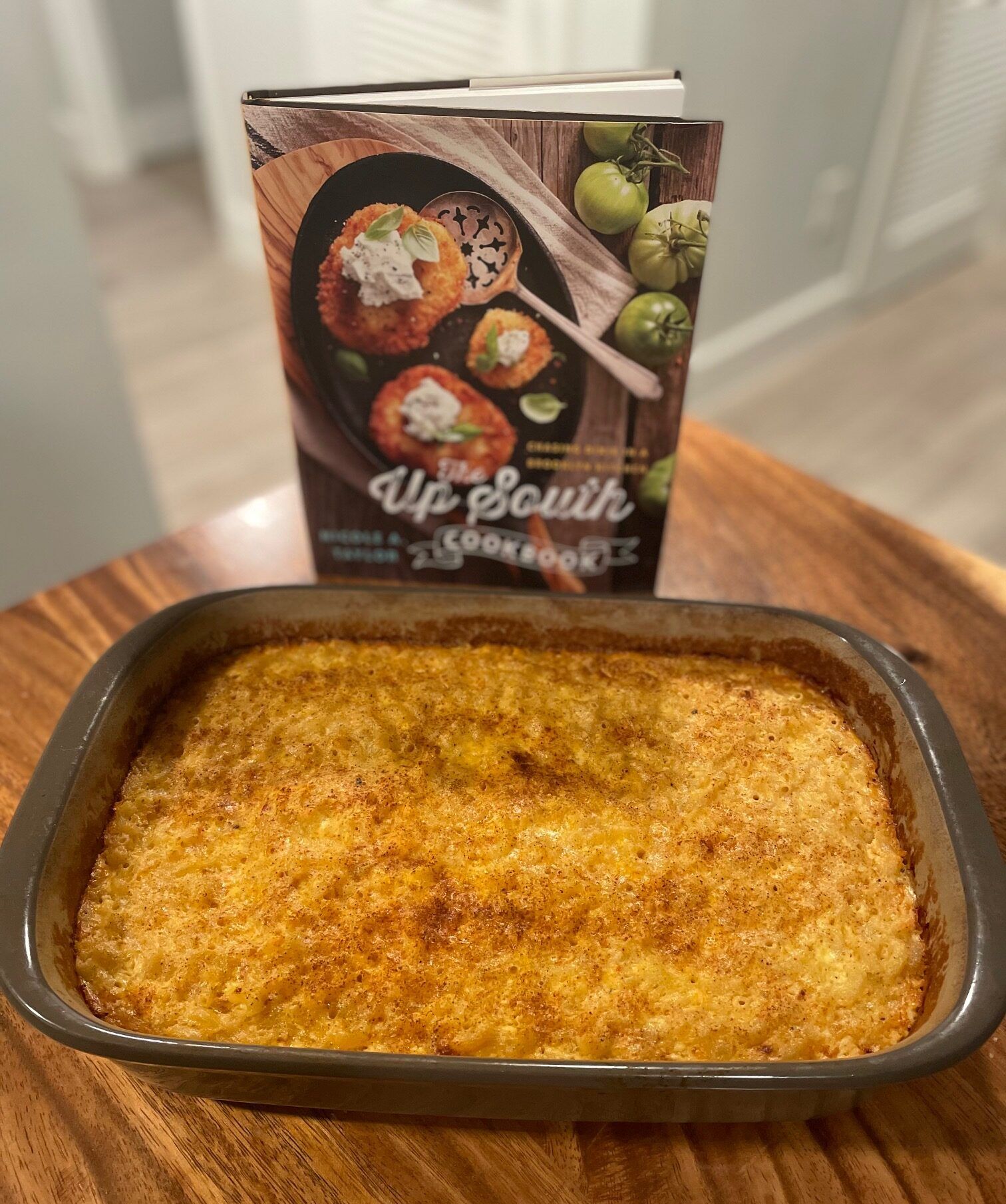 A casserole dish of baked mac and cheese in front of The Up South Cookbook