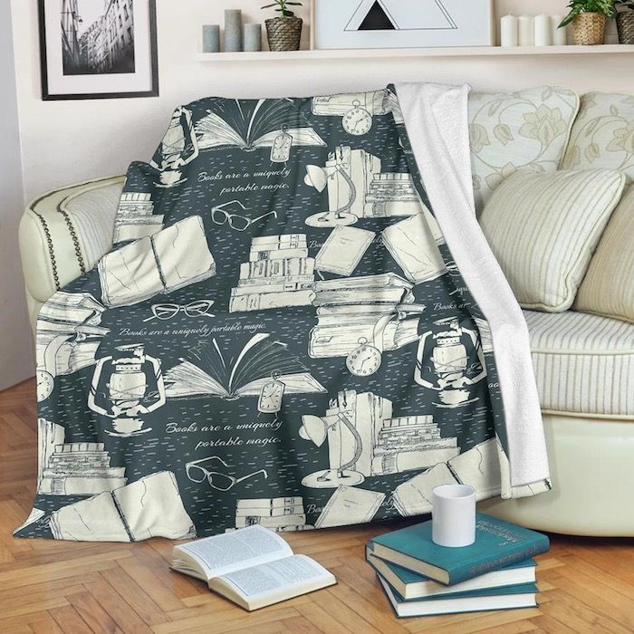 a grey blue and cream blanket in a book pattern spread over a cream-colored couch