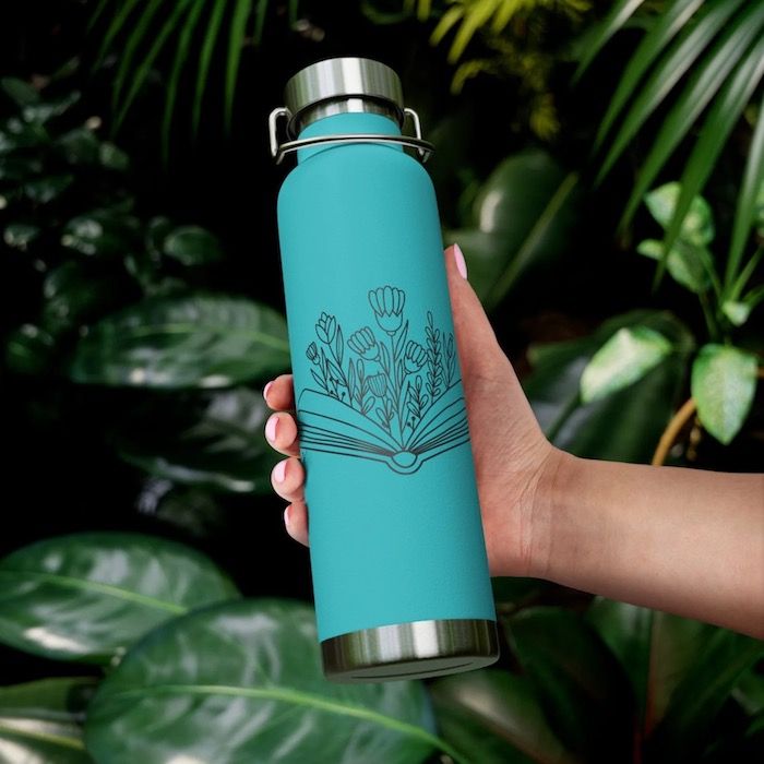 a turquoise insulated water bottle with a book and flower design on the front