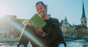 Black man with tan skin reading with pretty castles in the background