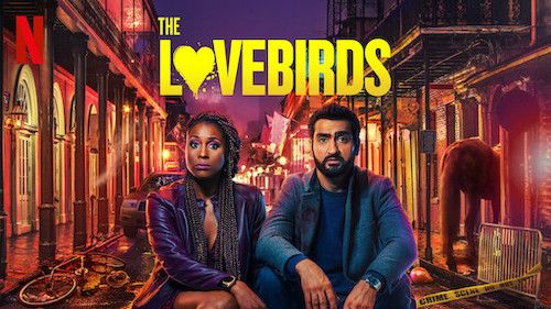 The Lovebirds film poster of Issa Rae and Kumail Nanjiani sitting on the street floor with a chaotic street behind them at night