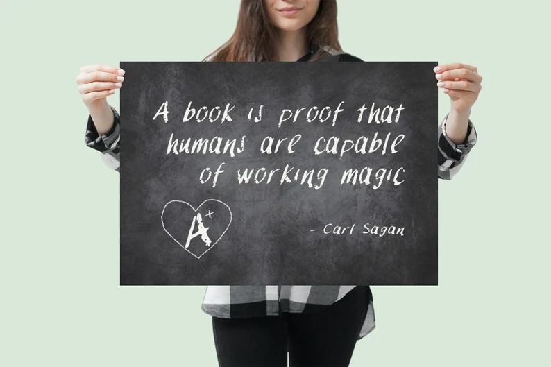 a photo of someone holding up a poster with the text "A book is proof that humans are capable of working magic." Carl Sagan