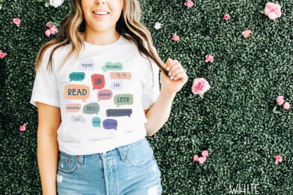 White tee-shirt with rainbow colored speech bubbles featuring the word "read" in various languages.