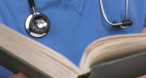 a close-up photo of someone wearing scrubs holding a book