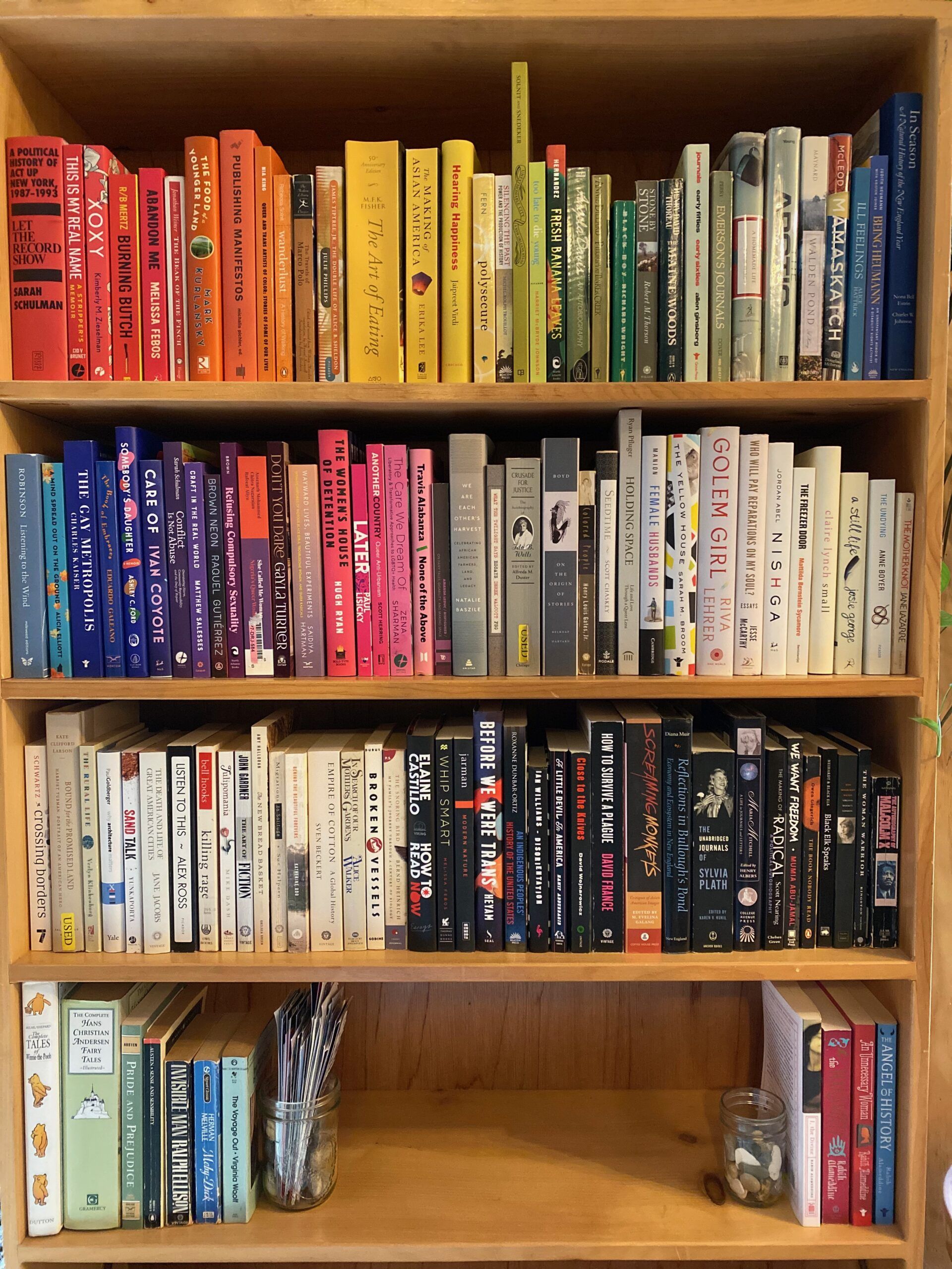 Closeup of a bookshelf with books arranged in rainbow order. 